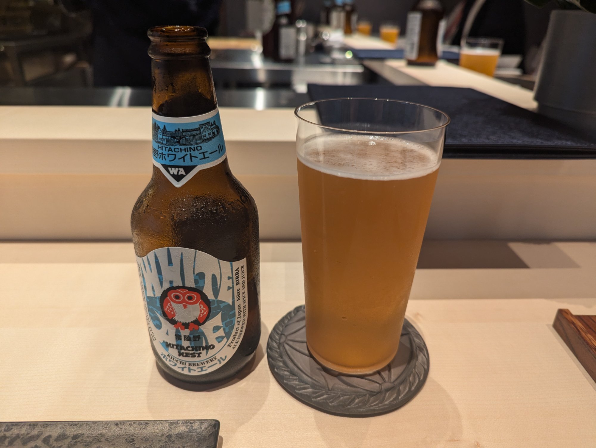Hitachino Nest White Ale bottle and glass alongside the counter atmosphere