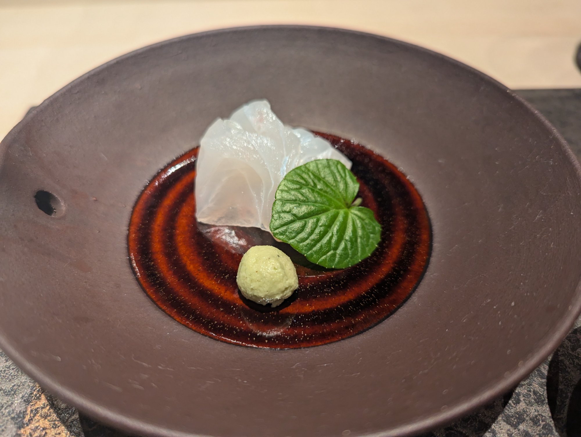 Tsukuri. Meitai from Karatsu on a Densaku-gama black vessel, the thin-cut fish luminous against the dark glaze