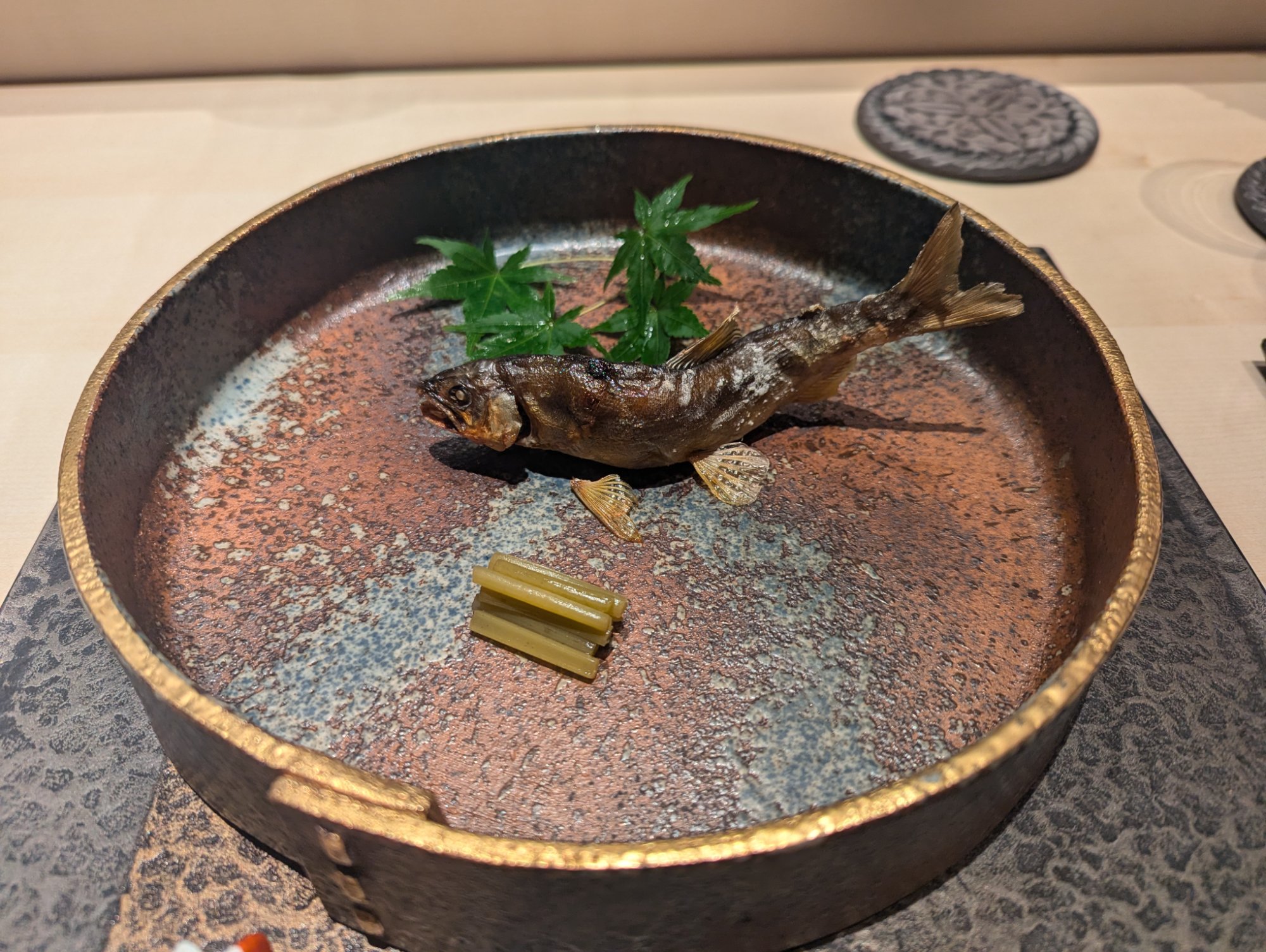 Yakimono. Salt-grilled ayu on a heavy iron-glaze plate with a gold rim