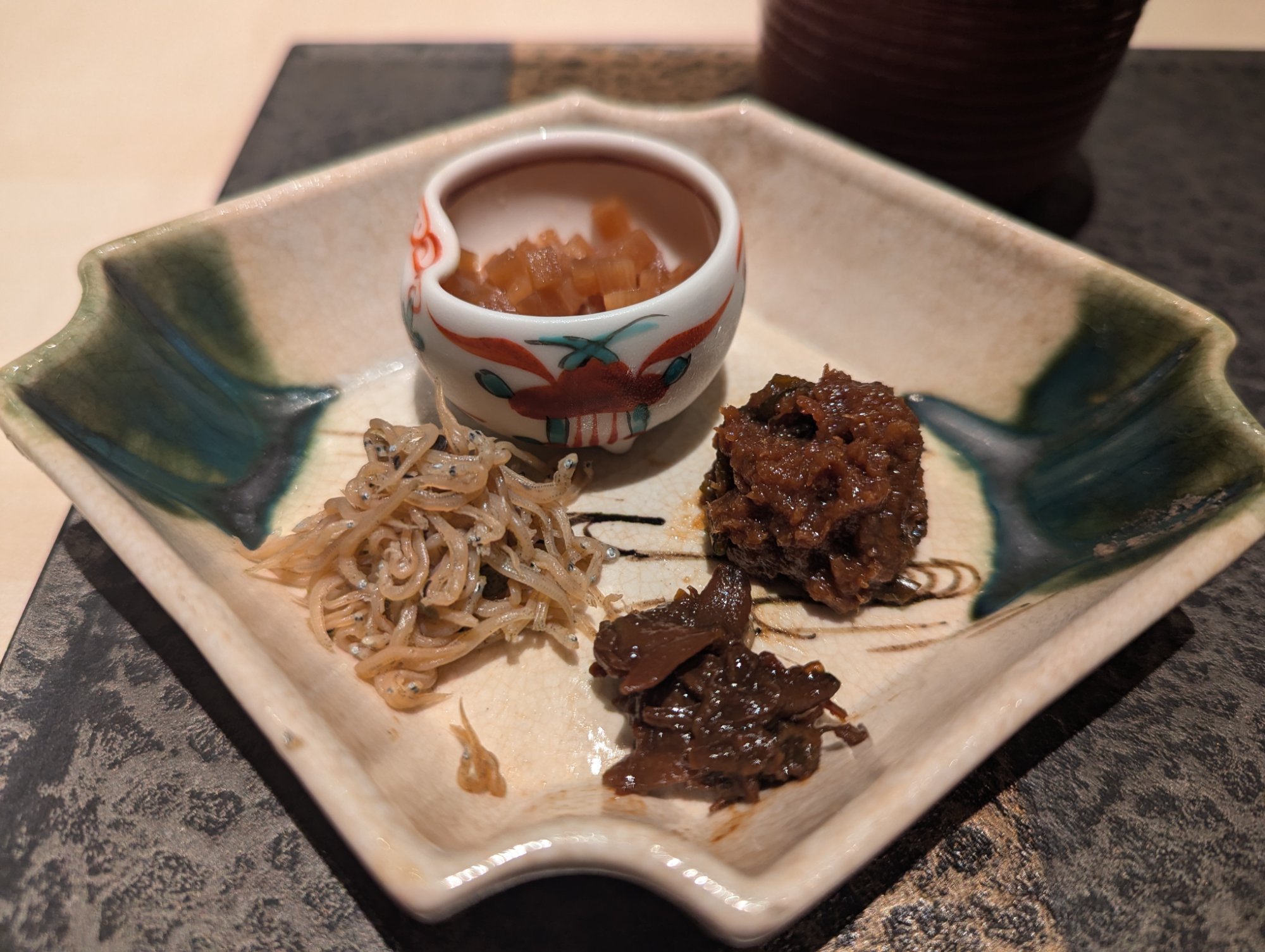 Rice accompaniments — whitebait, tsukudani, and pickles arranged in painted small dishes
